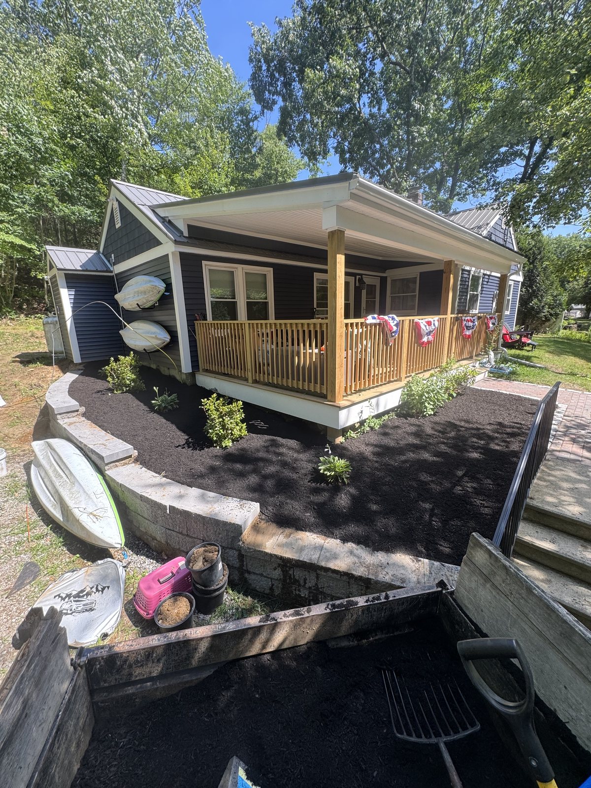 New mulch bed, shrubs, and a curved retaining wall at the front porch of a cottage