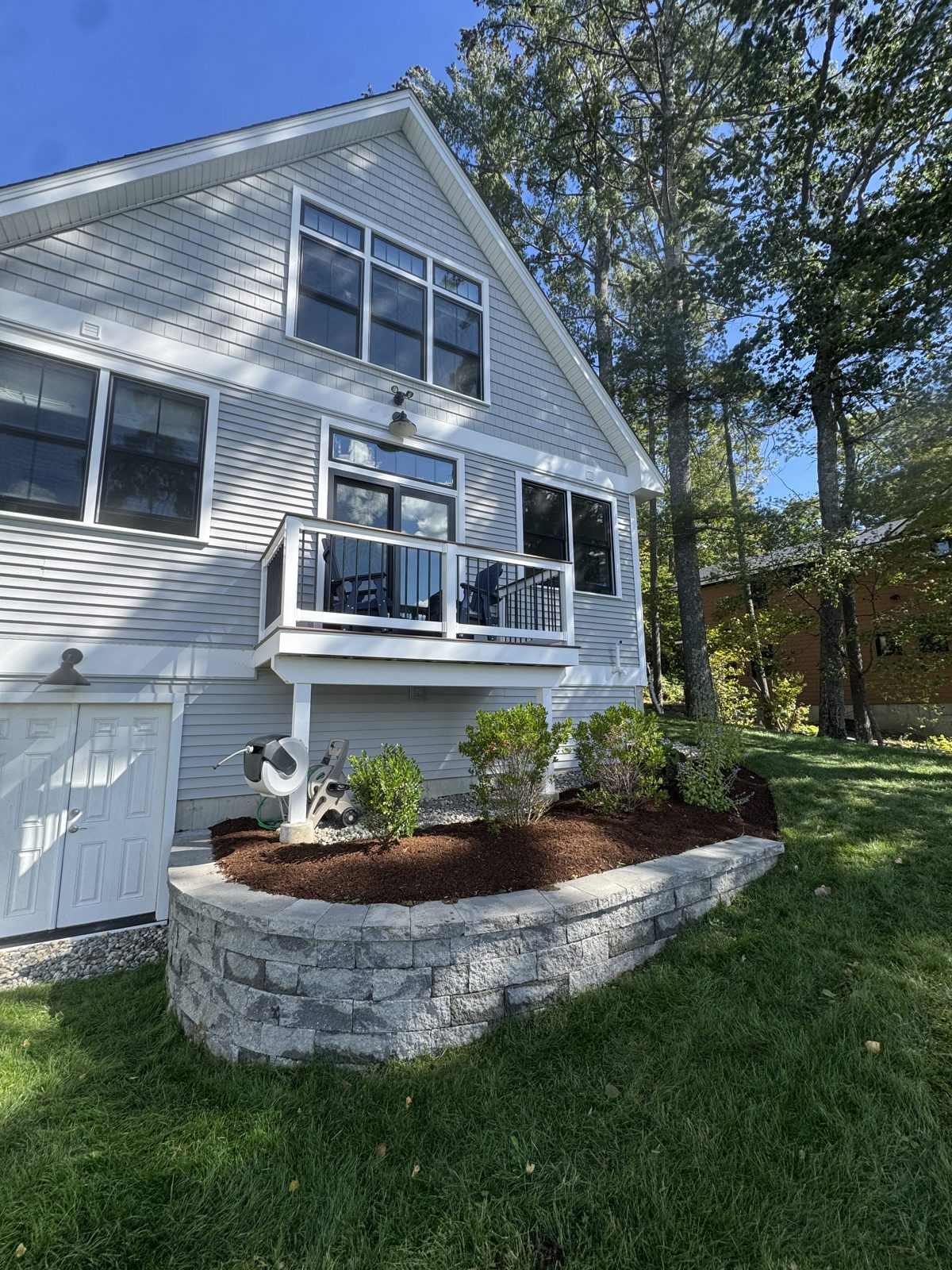 Curved stone retaining wall with a fresh mulch bed beside a home
