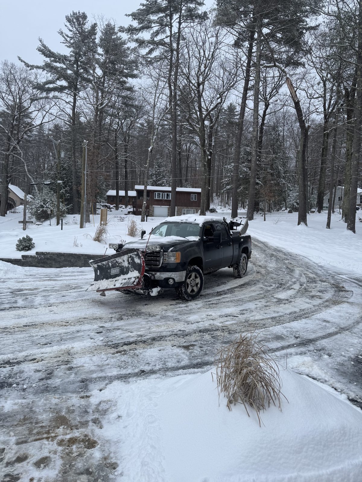 Pickup truck with a plow clearing a parking lot during a snowstorm