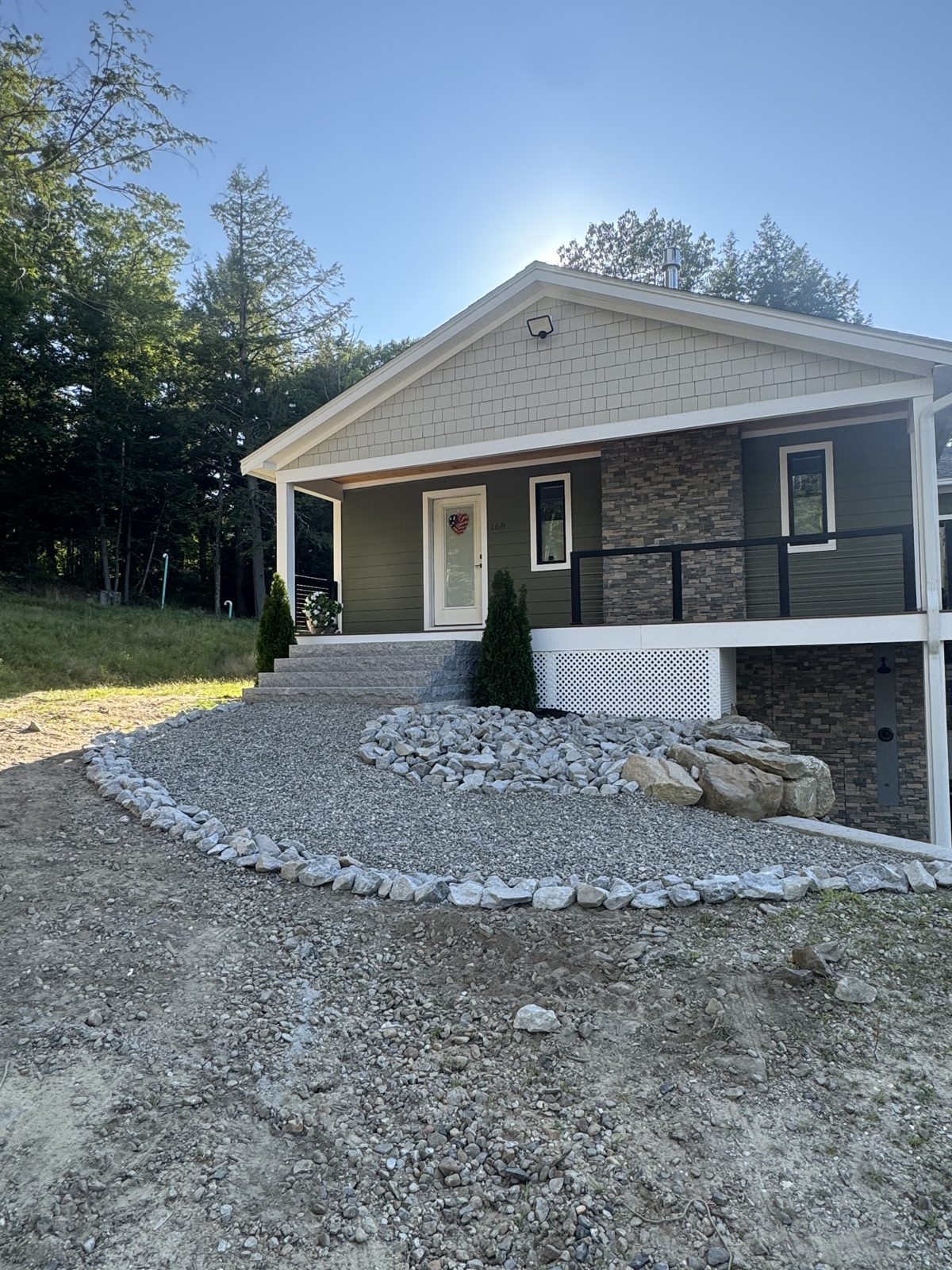 Curved river stone bed and gravel border around a new home