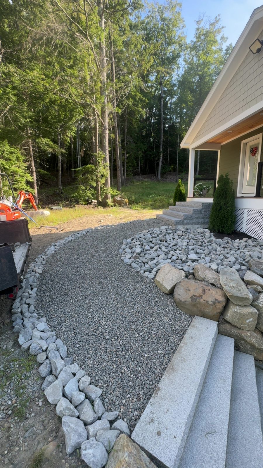 Gravel path edged with river stone beside boulders and granite steps