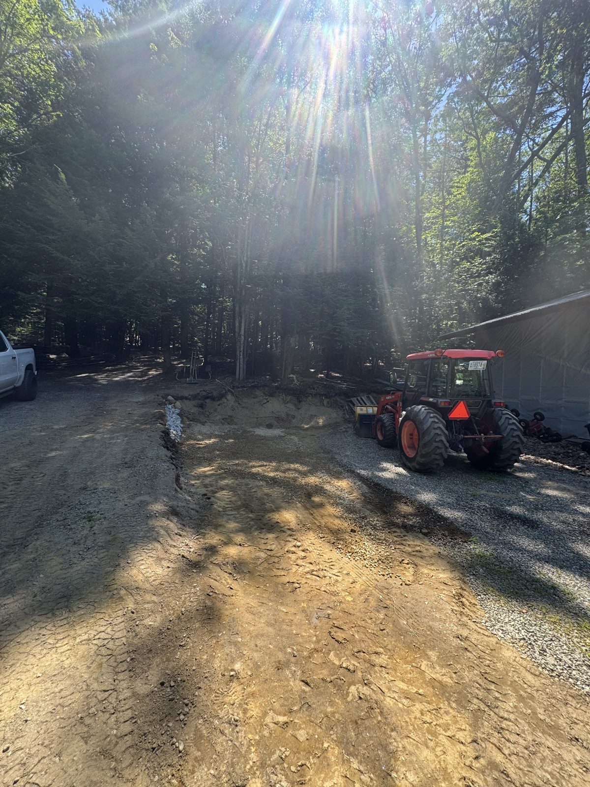 Tractor grading a dirt driveway in the woods